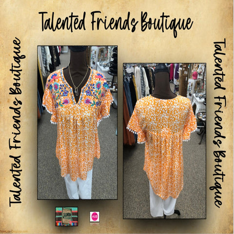 Orange and white animal print paired with floral embroidery, split neckline, short ruffle sleeve, and white pom pom fringe detail